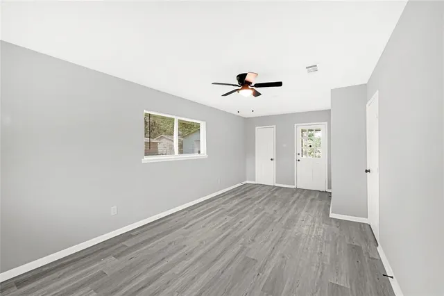 an empty room with wooden floor and windows