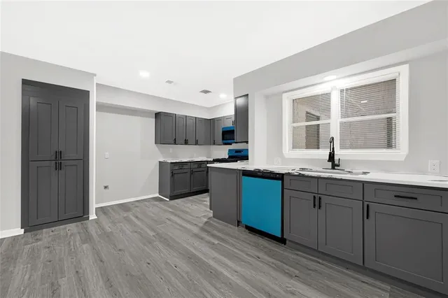 a kitchen with stainless steel appliances granite countertop a sink cabinets and wooden floor