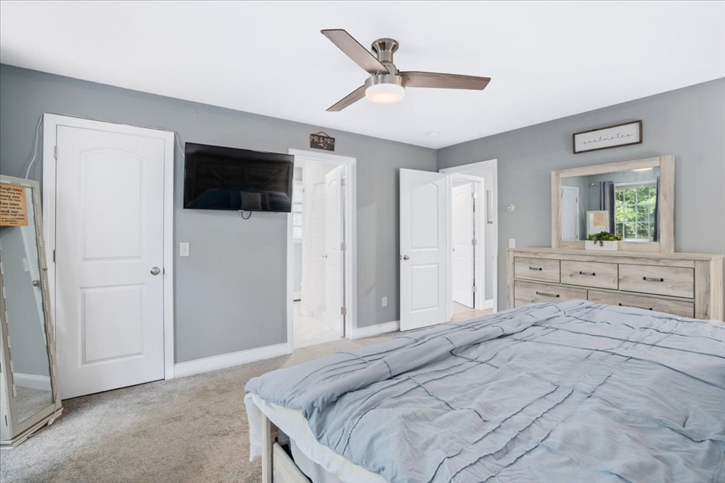61 Blake Road Epping, NH 03042 - Photo 24 of 41 a bedroom with a large bed a flat tv screen and a ceiling fan