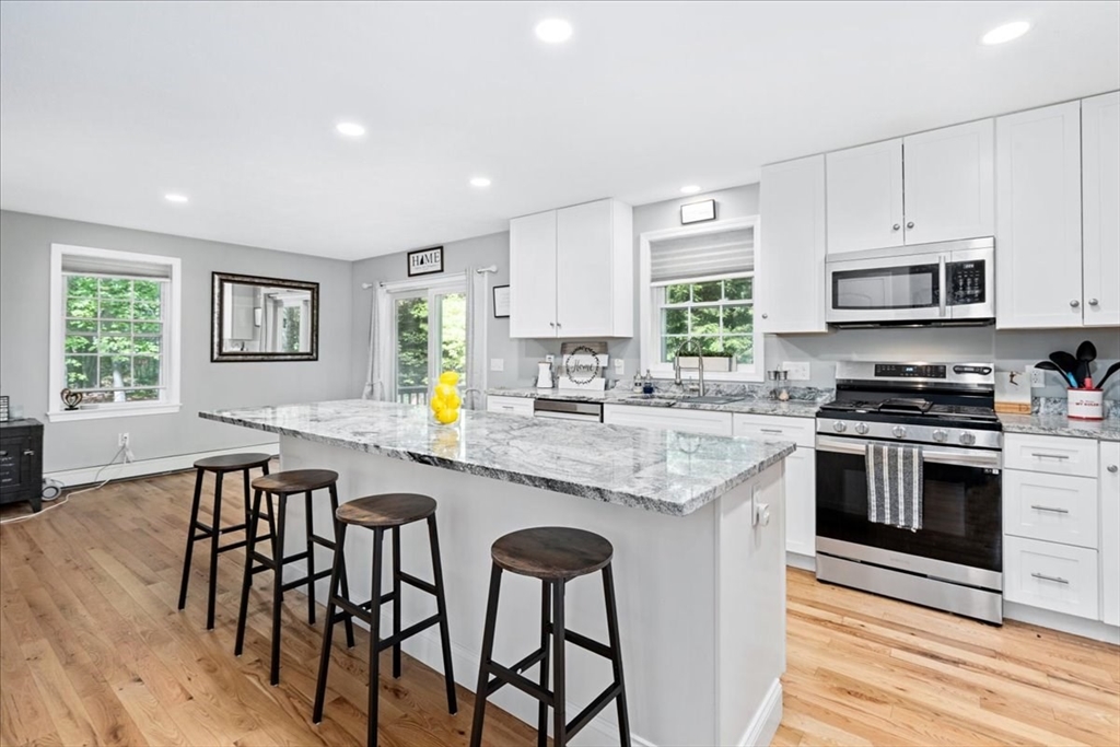 61 Blake Road Epping, NH 03042 - Photo 7 of 41 a kitchen with stainless steel appliances granite countertop a stove a sink a microwave a dining table and chairs