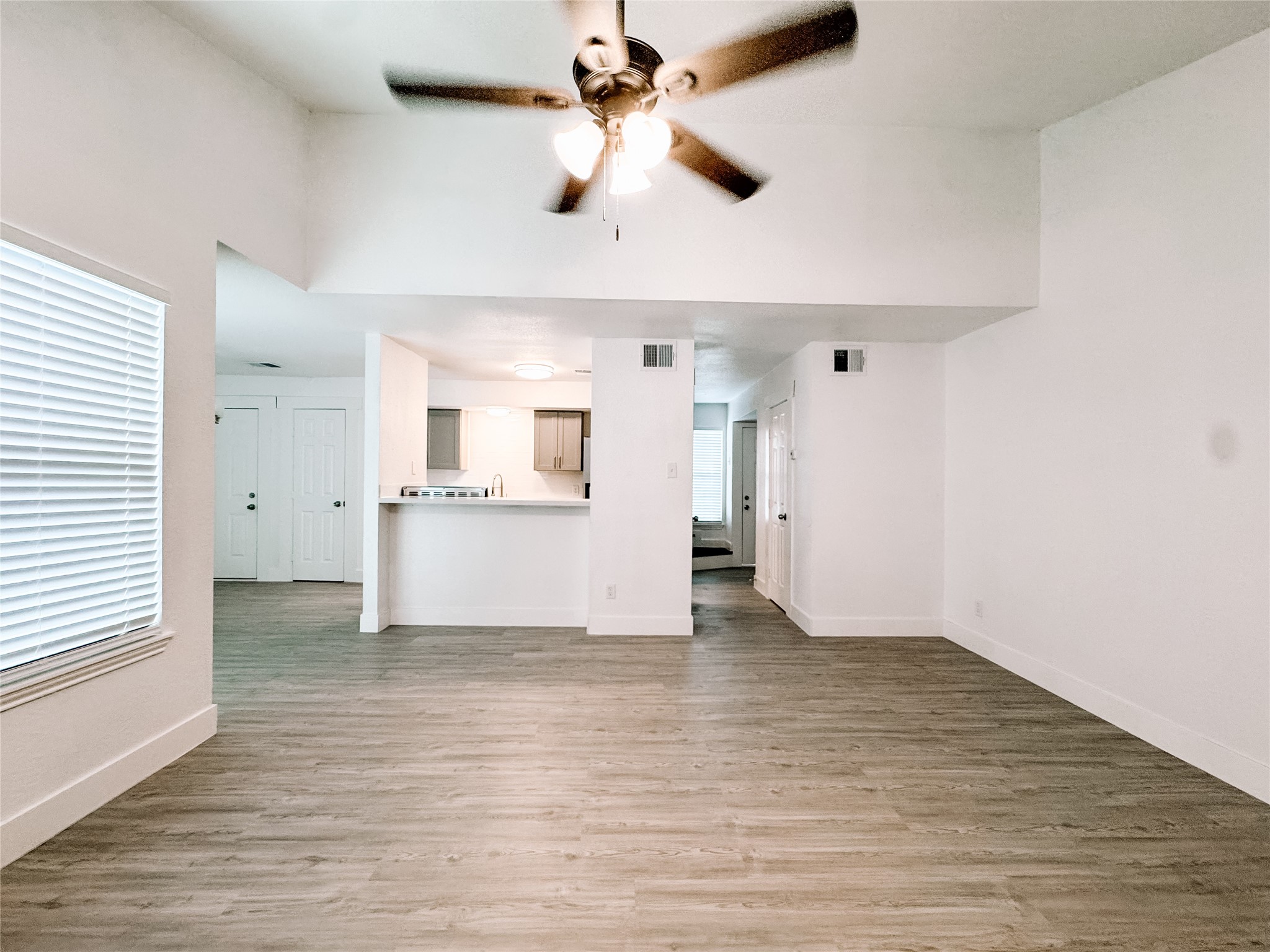 a view of an empty room with window and wooden floor