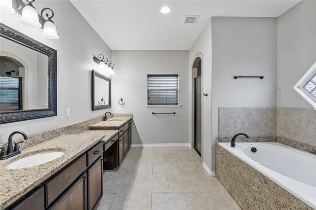 a spacious bathroom with a granite countertop tub double vanity sink and a mirror