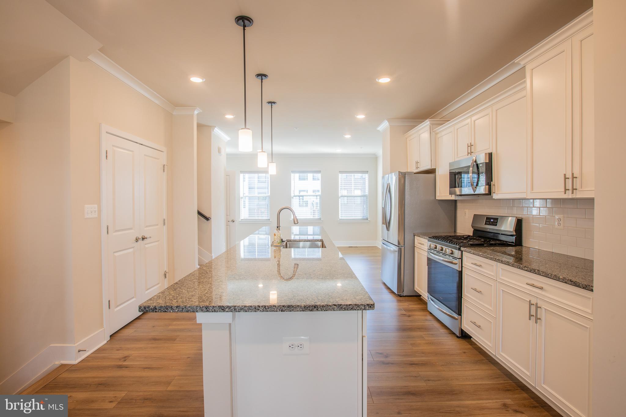 826 Teacher MItchell Road Glen Burnie, MD 21060 - Photo 10 of 41 a kitchen with stainless steel appliances granite countertop a sink stove and white cabinets with wooden floor
