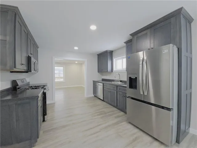 a kitchen with stainless steel appliances granite countertop a refrigerator a stove and a sink