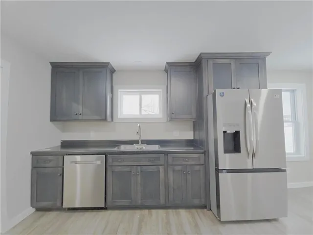 a kitchen with a sink a refrigerator and white cabinets