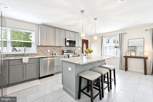 a kitchen with kitchen island granite countertop a table chairs microwave and sink