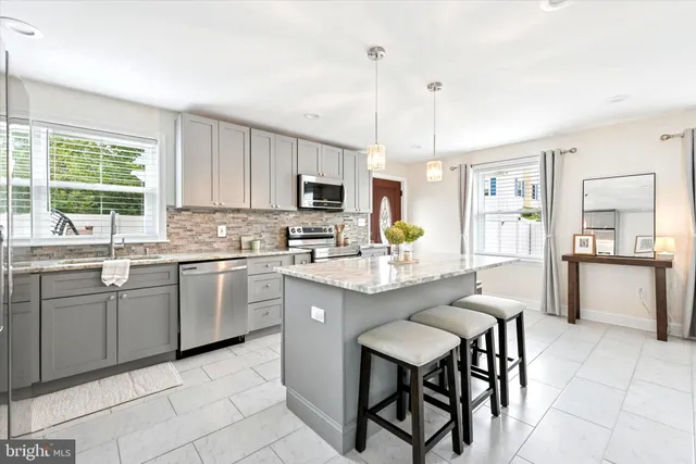 a kitchen with kitchen island granite countertop a table chairs microwave and sink