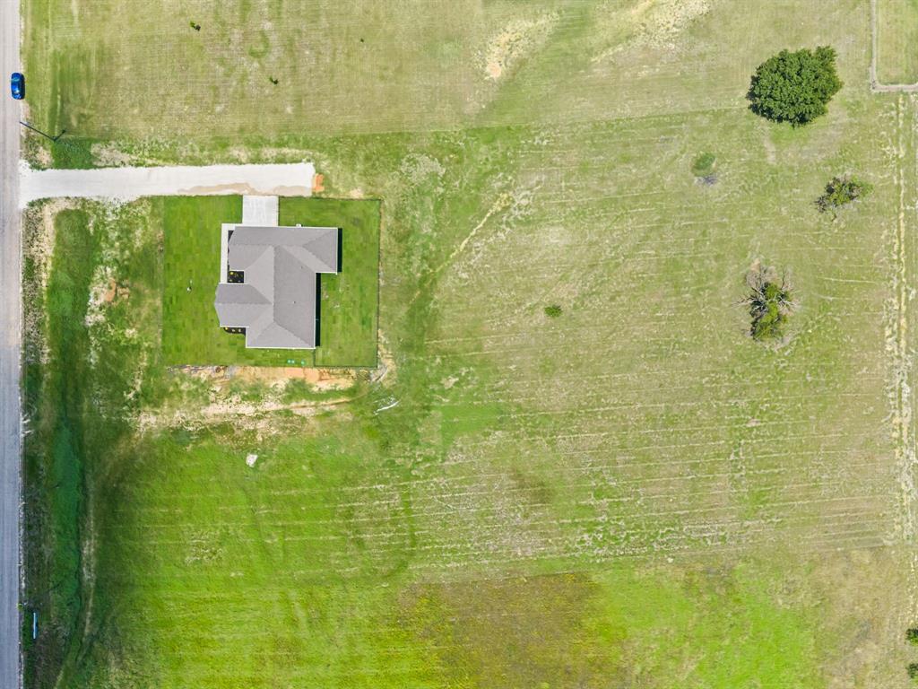 2705 Gospel Road Tolar, TX 76476 - Photo 36 of 36 Aerial perspective showcasing a single-story residence with a grey shingle roof, situated on a substantial green lot
