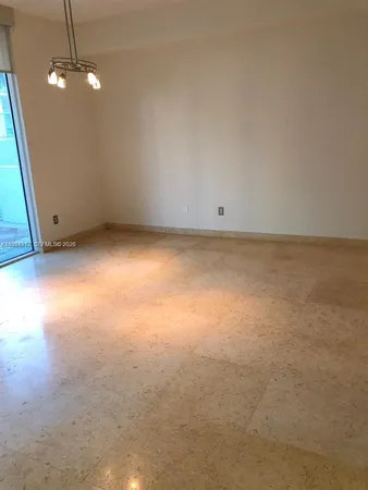 an empty room with a chandelier fan and windows