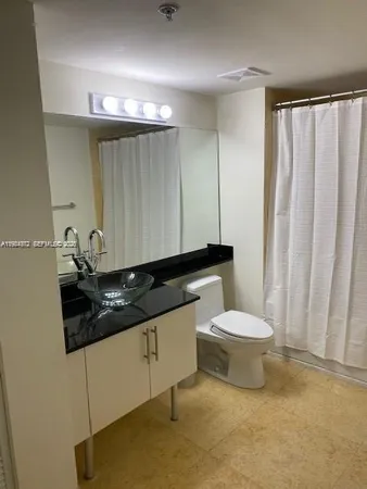 a bathroom with a granite countertop sink a toilet and a mirror