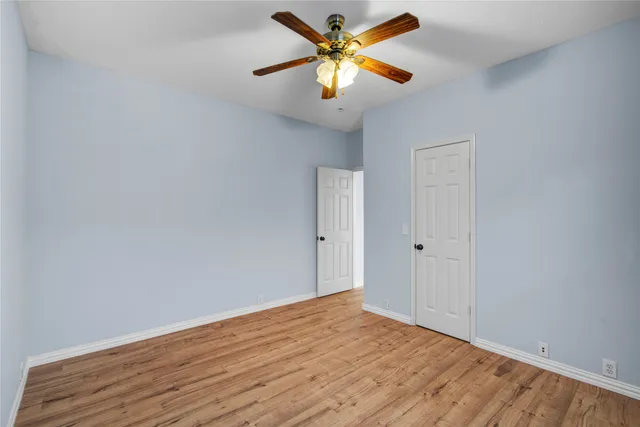 a view of a room with wooden floor and a ceiling fan