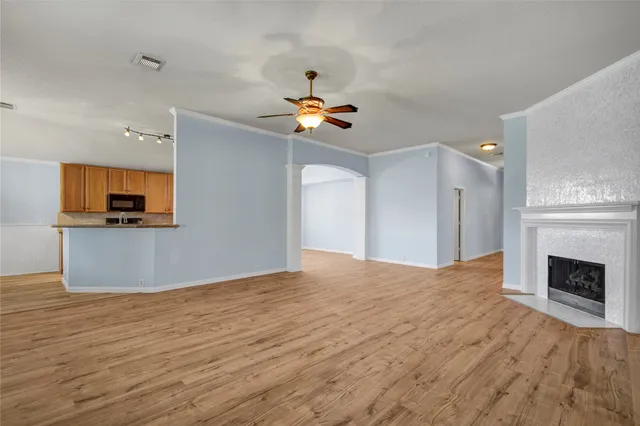 a view of an empty room with a fireplace and wooden floor