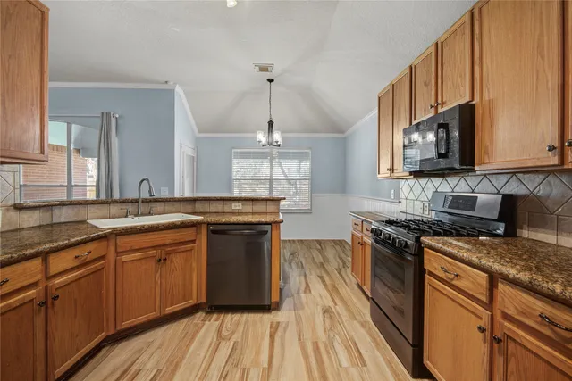 a kitchen with stainless steel appliances granite countertop hardwood floor sink stove and granite counter top