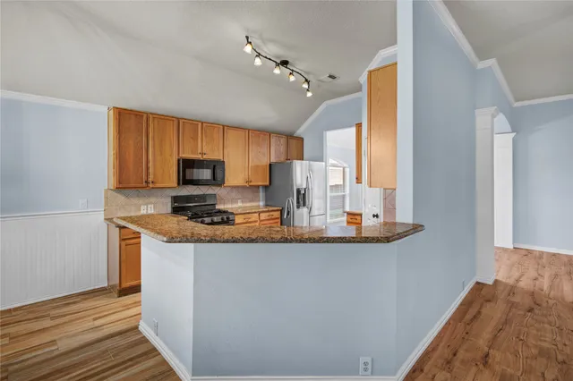 a kitchen with stainless steel appliances granite countertop a stove a sink and a refrigerator