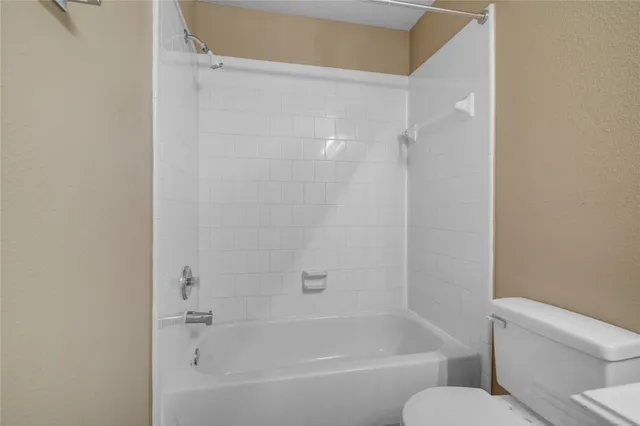 a white bath tub sitting next to a white toilet and vanity