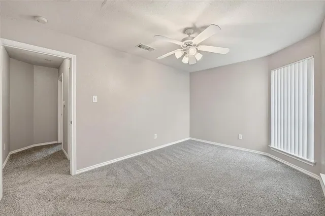 an empty room with windows and fan
