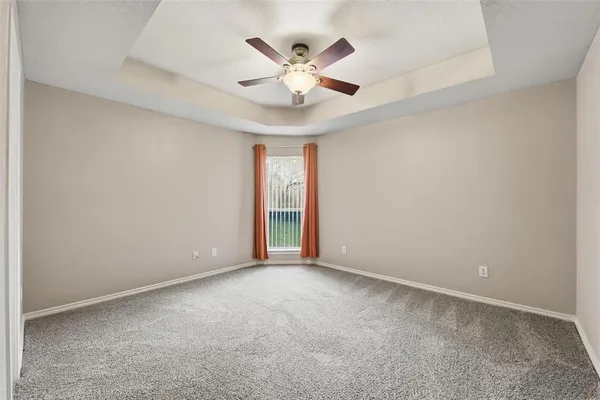 an empty room with ceiling fan and window