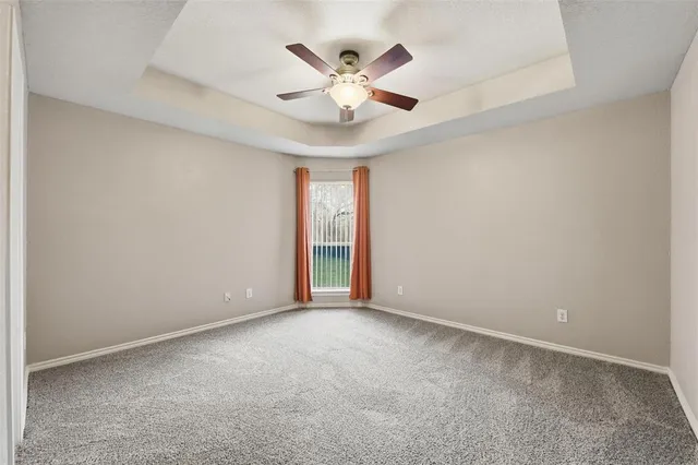 an empty room with ceiling fan and window