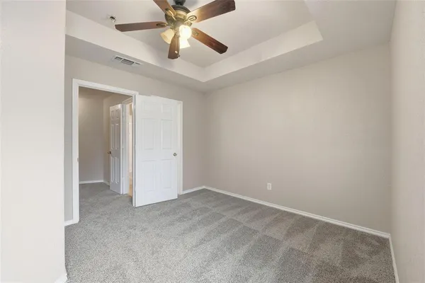 an empty room with a fan & a ceiling fan