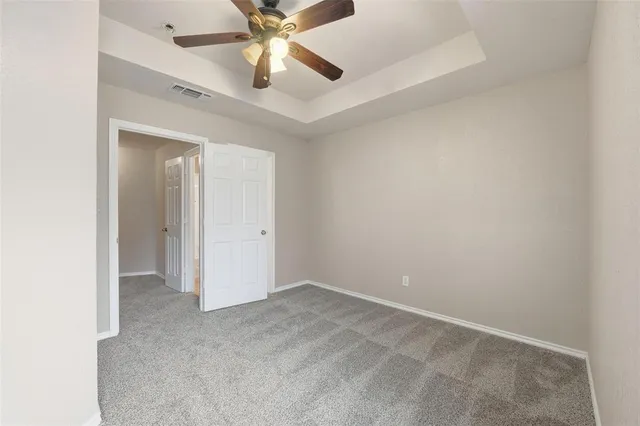 an empty room with a fan & a ceiling fan