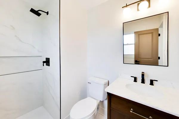 a bathroom with a sink vanity mirror and toilet