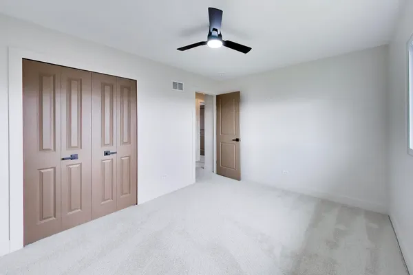 a view of an empty room and chandelier fan