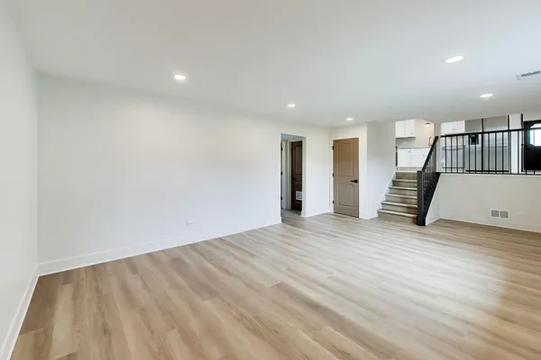 a view of an empty room with wooden floor and stairs