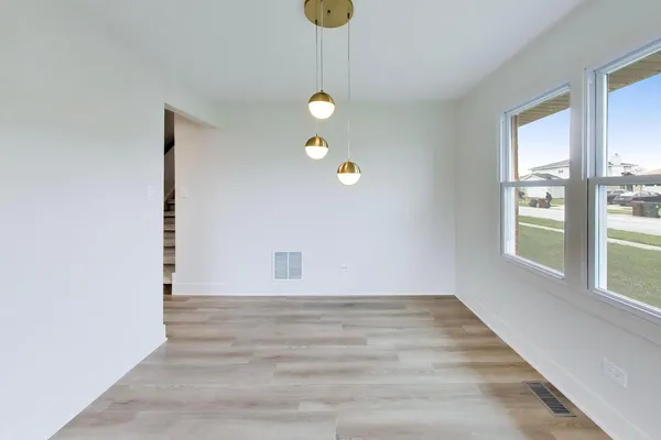 a view of an empty room with window and wooden floor