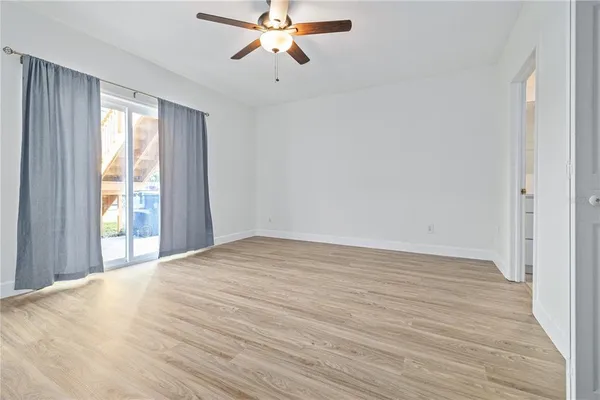 a view of an empty room with wooden floor and a window