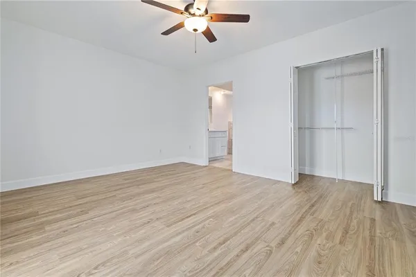 an empty room with wooden floor fan and windows