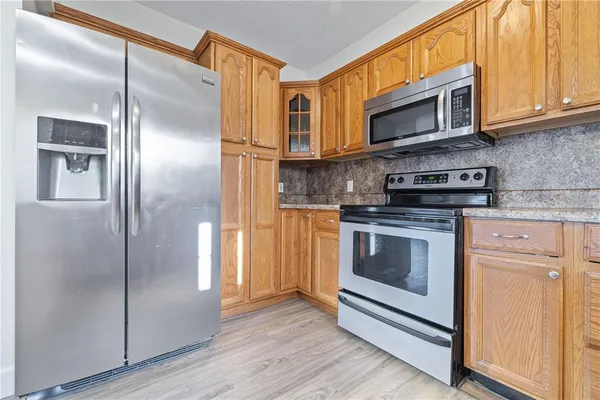 a kitchen with stainless steel appliances granite countertop a refrigerator microwave and stove top oven