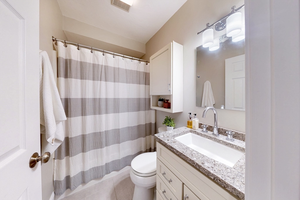 111 West 8th Street, Unit C Boston, MA 02127 - Photo 17 of 22 a bathroom with a granite countertop sink toilet a mirror and shower curtain