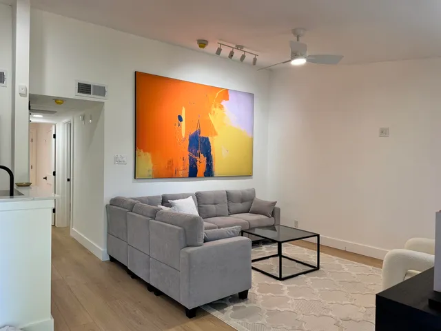 a living room with stainless steel appliances kitchen island granite countertop furniture and a wooden floor