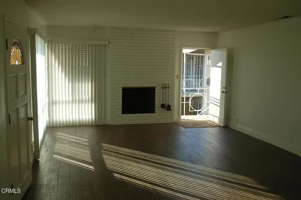 a view of an empty room with wooden floor and a fireplace