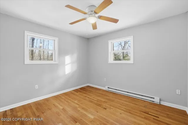 a view of empty room with wooden floor and fan