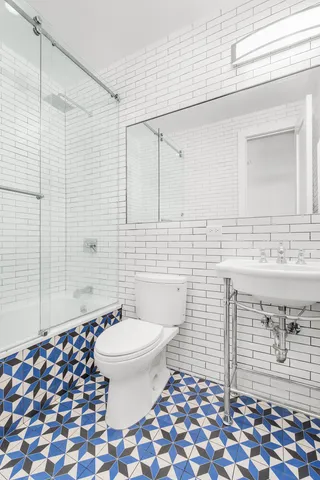 a bedroom with a bed a mirror on dresser and a window