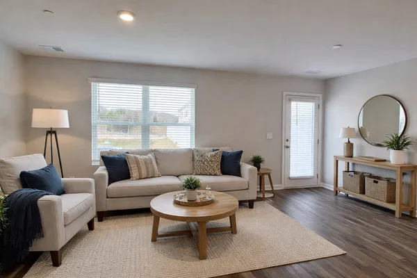 a living room with furniture a rug a lamp and a large window