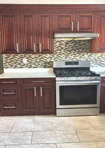 a stove top oven sitting inside of a kitchen with granite countertop wooden cabinets