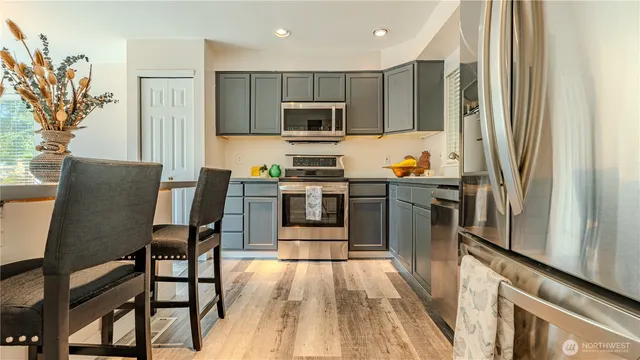 a kitchen with stainless steel appliances granite countertop a refrigerator a stove top oven a sink dishwasher and wooden cabinets with wooden floor