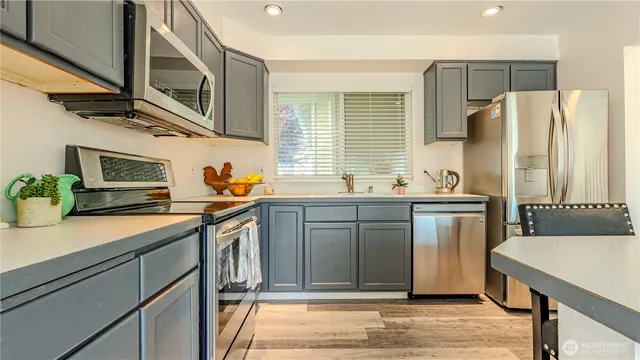 a kitchen with stainless steel appliances granite countertop a sink a stove cabinets and wooden floor