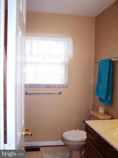 85 Walnut Creek Road Huntingtown, MD 20639 - Photo 13 of 19 a bathroom with a toilet a sink a window and mirror