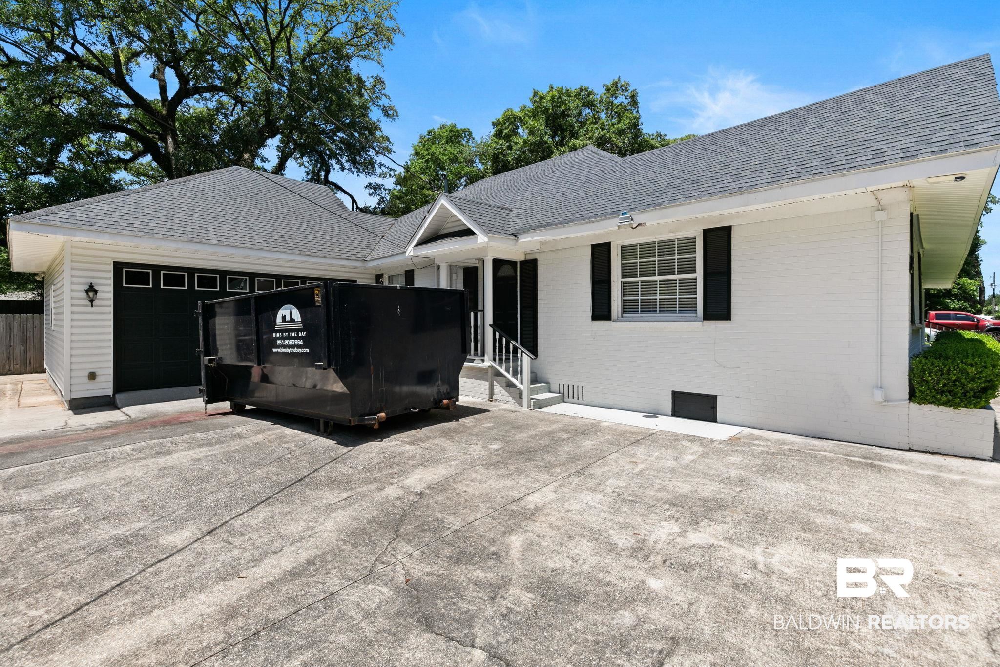 927 Cleveland Road Saraland, AL 36571 - Photo 49 of 80 White brick exterior featuring dark shutters, a contrasting dark garage door, and a prominent front entrance with white railings