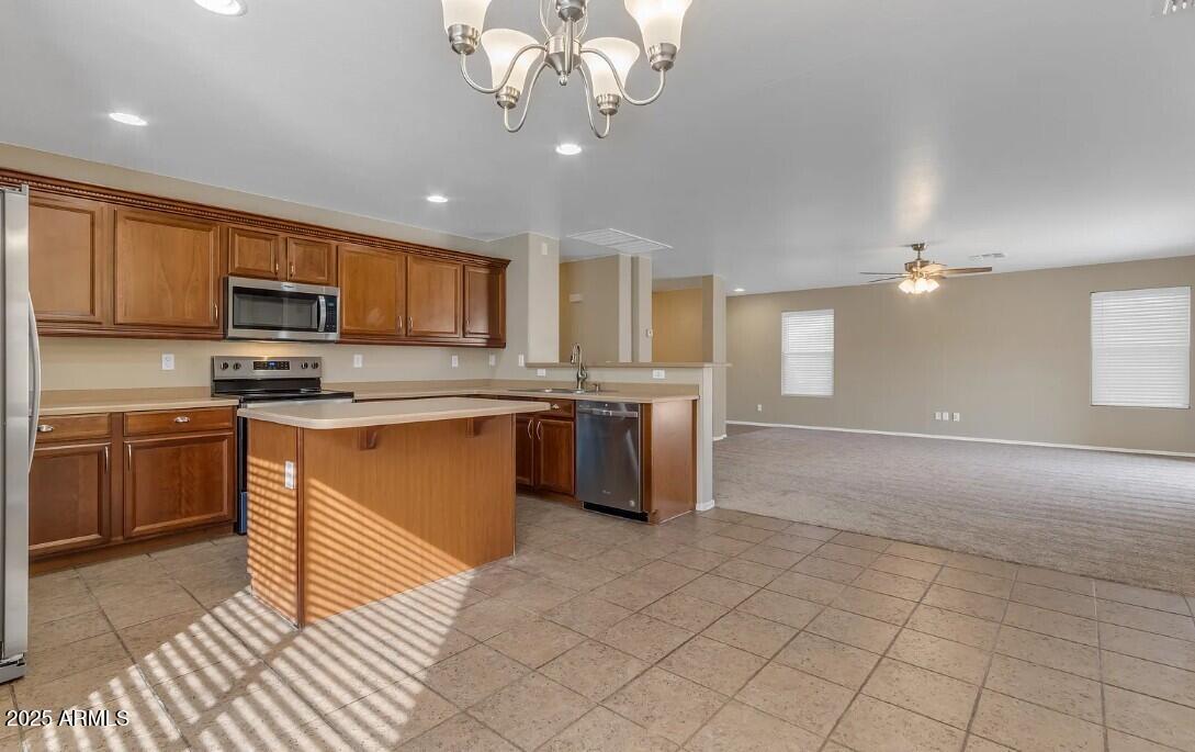 2199 West Tanner Ranch Road San Tan Valley, AZ 85144 - Photo 15 of 38 a kitchen with stainless steel appliances granite countertop a stove top oven a sink dishwasher a refrigerator and a dining table with wooden floor