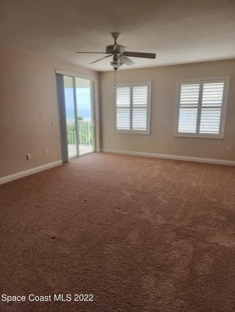 an empty room with windows and chandelier fan