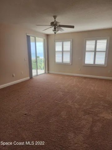 an empty room with windows and chandelier fan