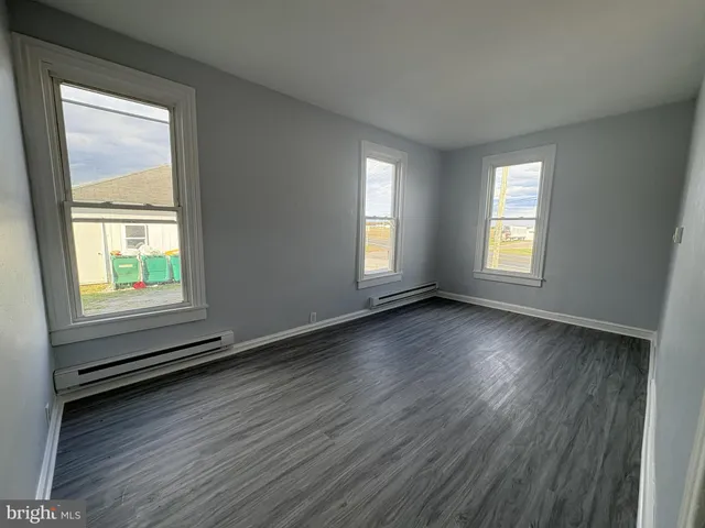 a view of an empty room with wooden floor and window