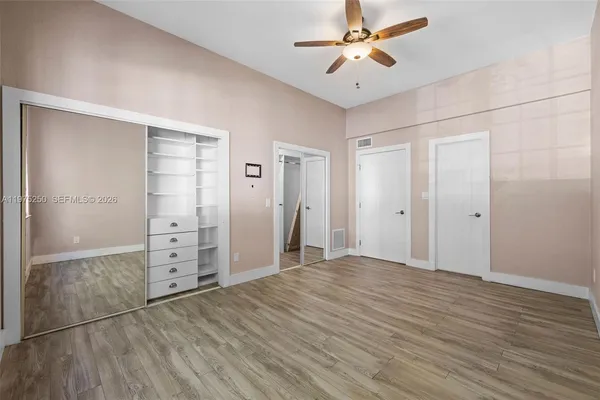an empty room with closet and a ceiling fan