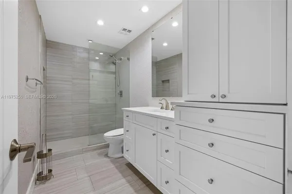a bathroom with a double vanity sink toilet mirror and shower