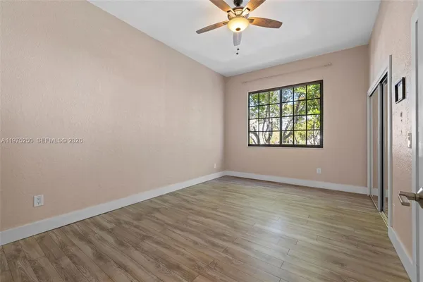 an empty room with wooden floor chandelier fan and windows