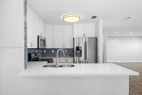 a kitchen with kitchen island stainless steel appliances a sink and a refrigerator